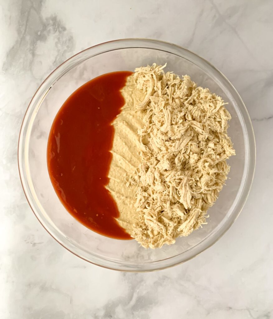 dairy free buffalo chicken dip base in a bowl with added hot sauce and shredded chicken