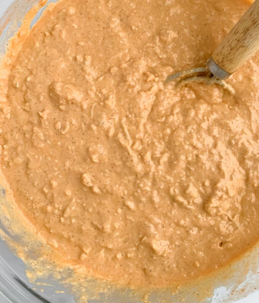 close up of dairy free buffalo chicken dip in a bowl with dutch whisk, after being mixed together