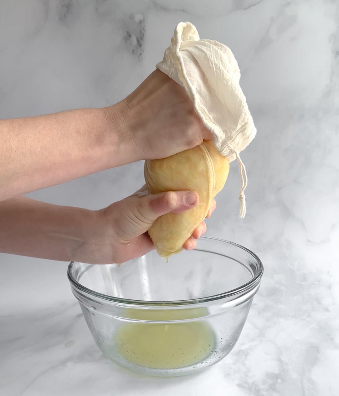 zucchini in a bag being squeezed over a bowl to catch excess liquid.