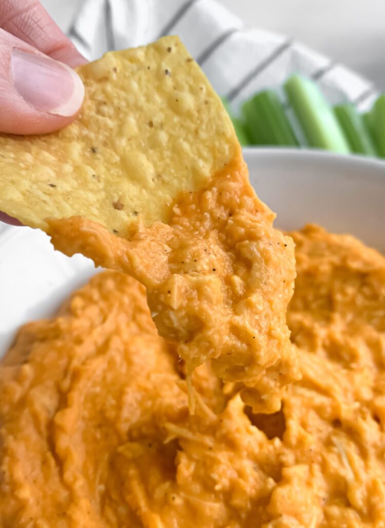 tortilla chip being dipped into chicken wing dip