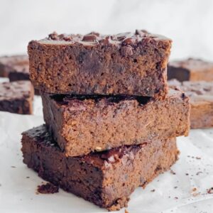 three brownies stacked on top of each other, with other brownies in the background.