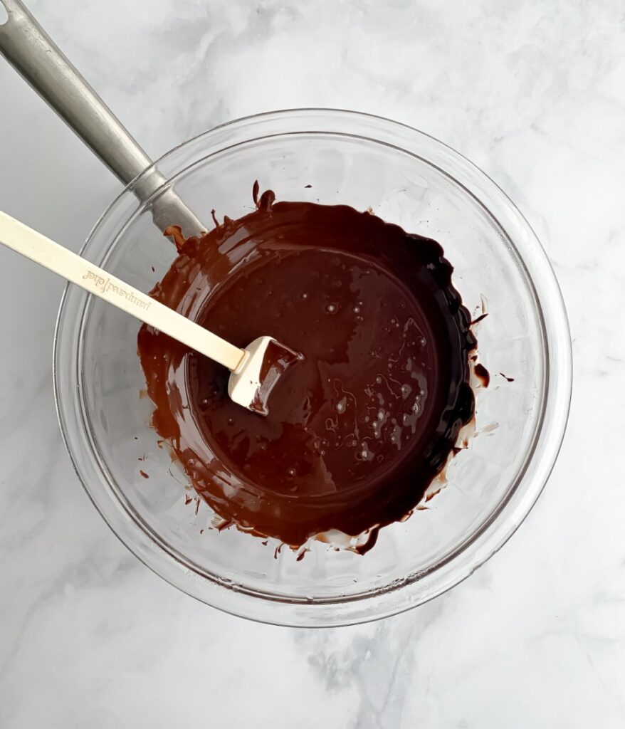 melted chocolate in a glass bowl with a spatula