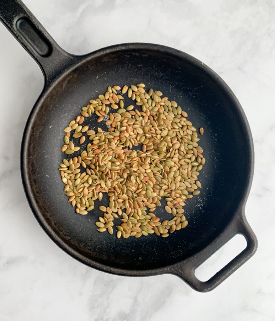 toasted pumpkin seeds in a cast iron skillet