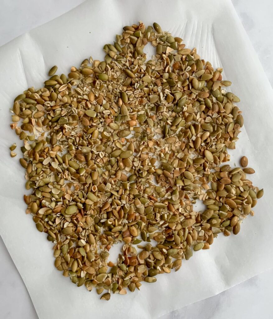 chopped up roasted pumpkin seeds on parchment paper