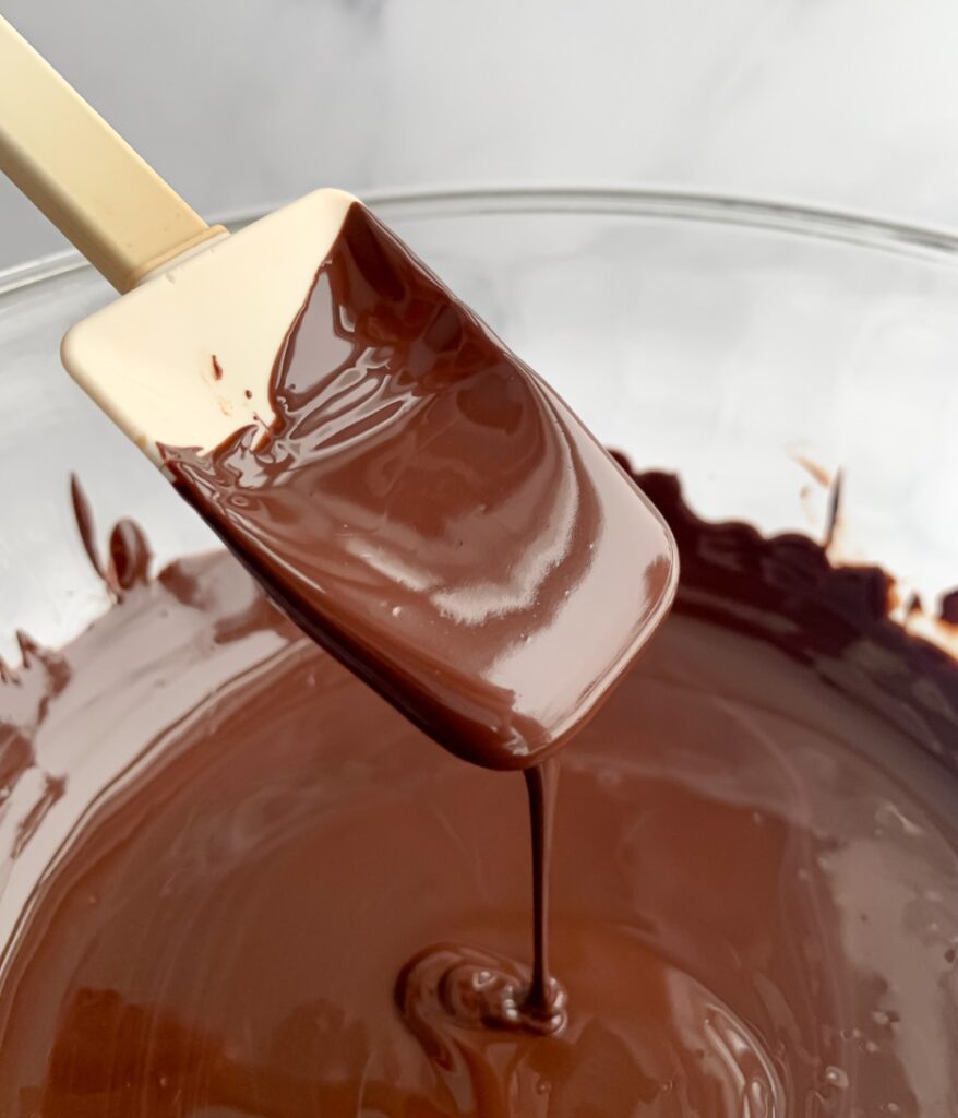 melted chocolate in a bowl drizzling from a spoon