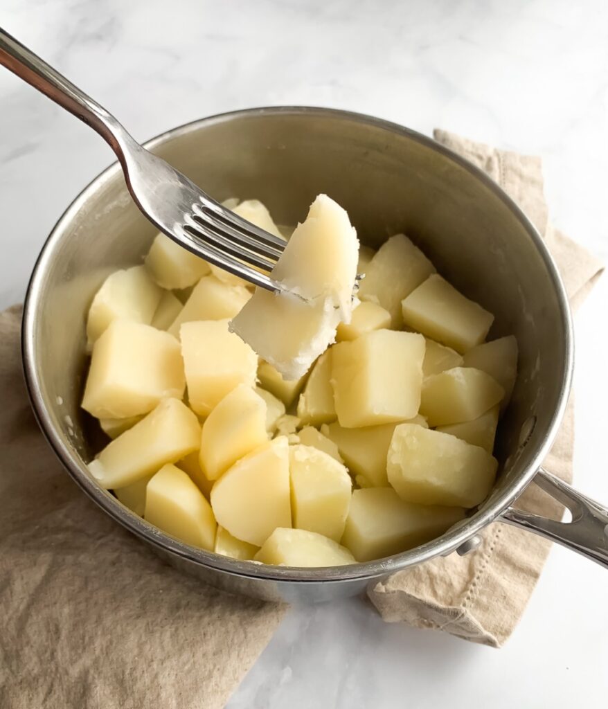 cooked potatoes in a pot with a fork showing its donness