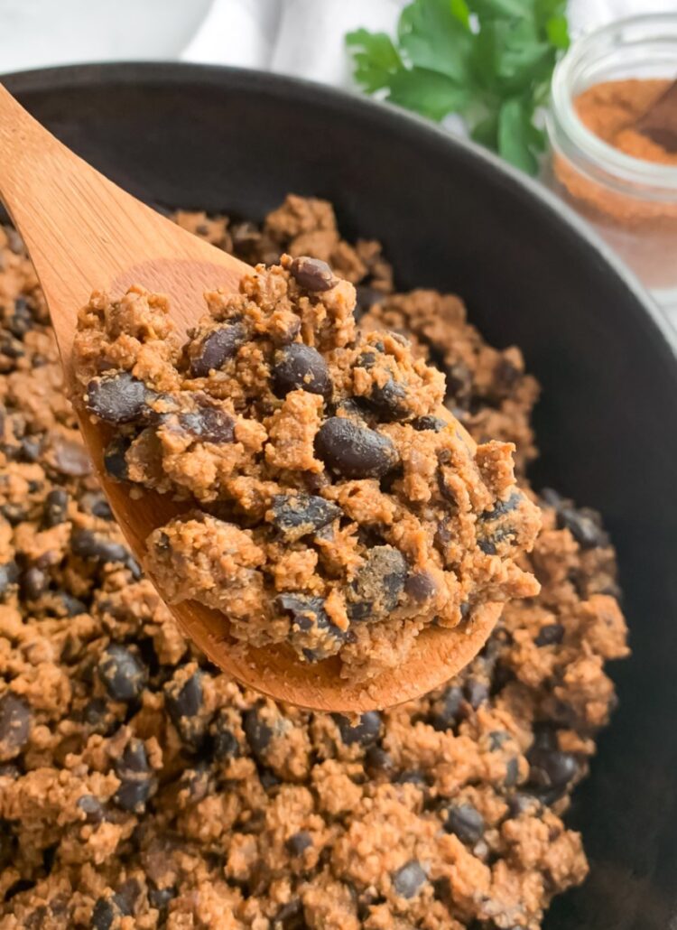 close up of taco meat with black beans on a wooden spoon