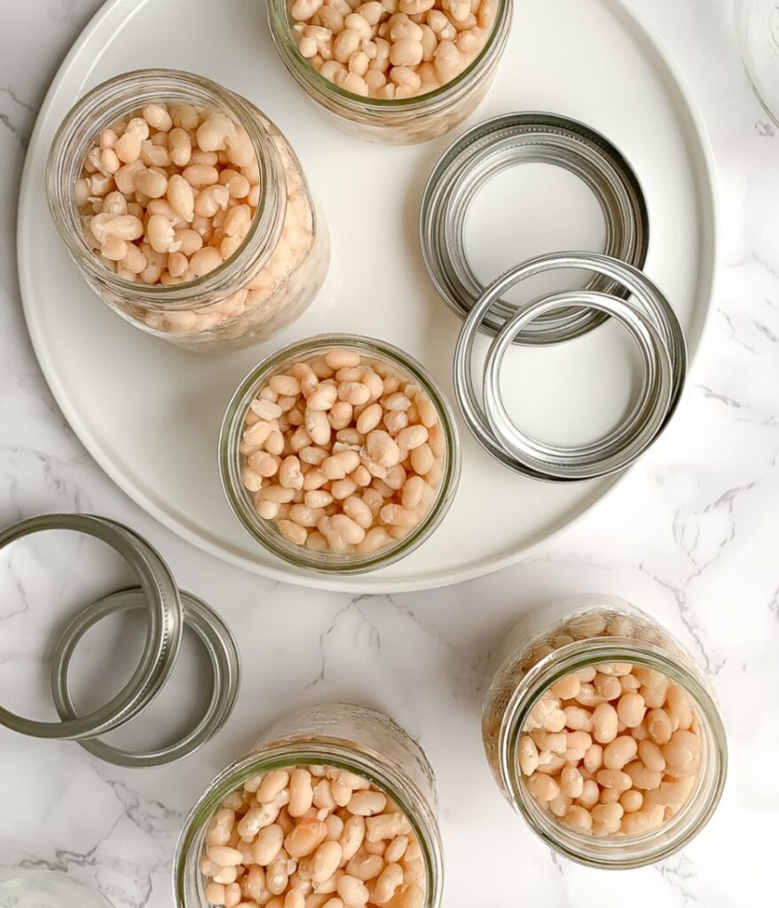 white beans in jars with metal lids to the side