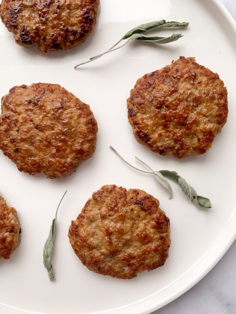 sausage patties on a white plate with dried sage leaves