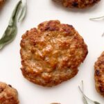 sausage patties on a white plate with dried sage leaves