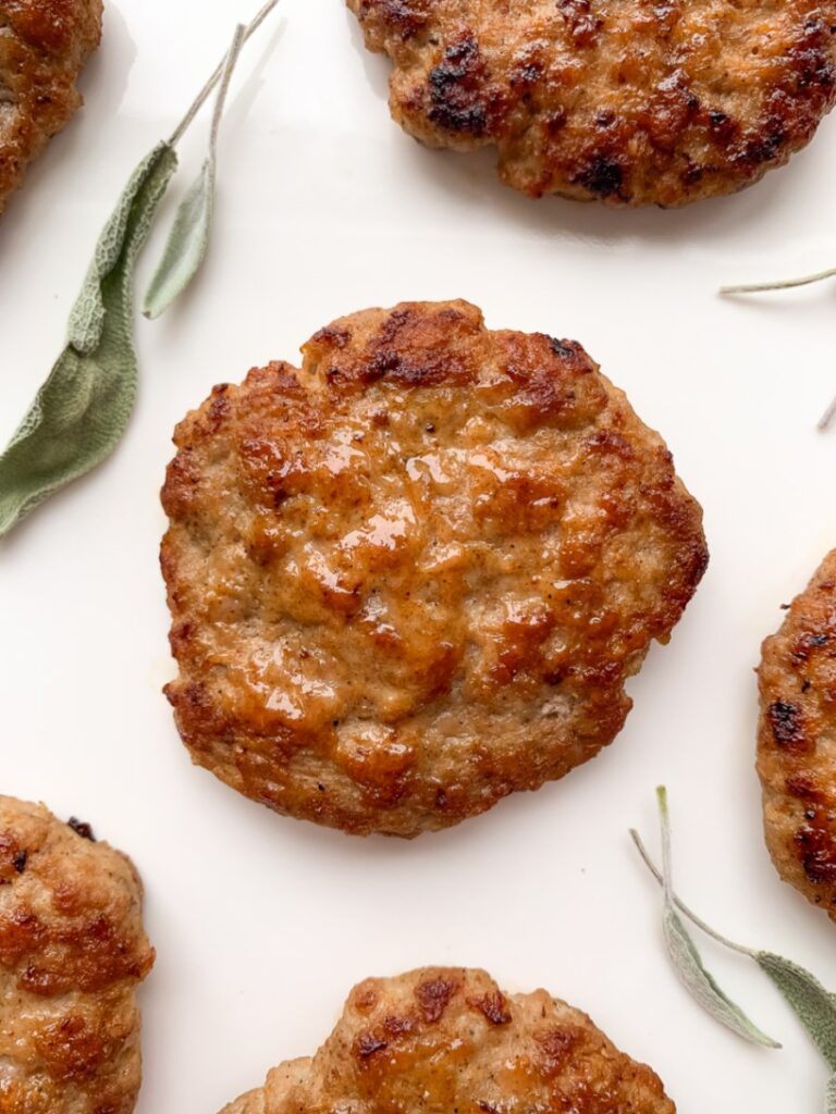 sausage patties on a white plate with dried sage leaves