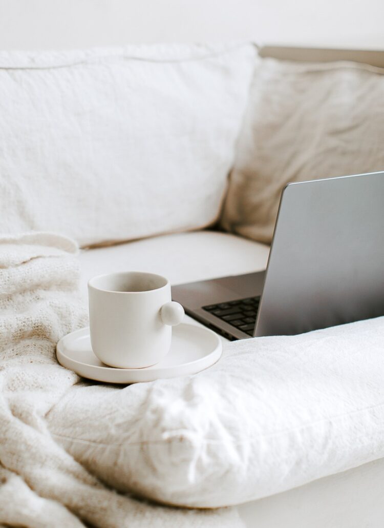 unique looking tea cup on a plate beside a laptop on a couch