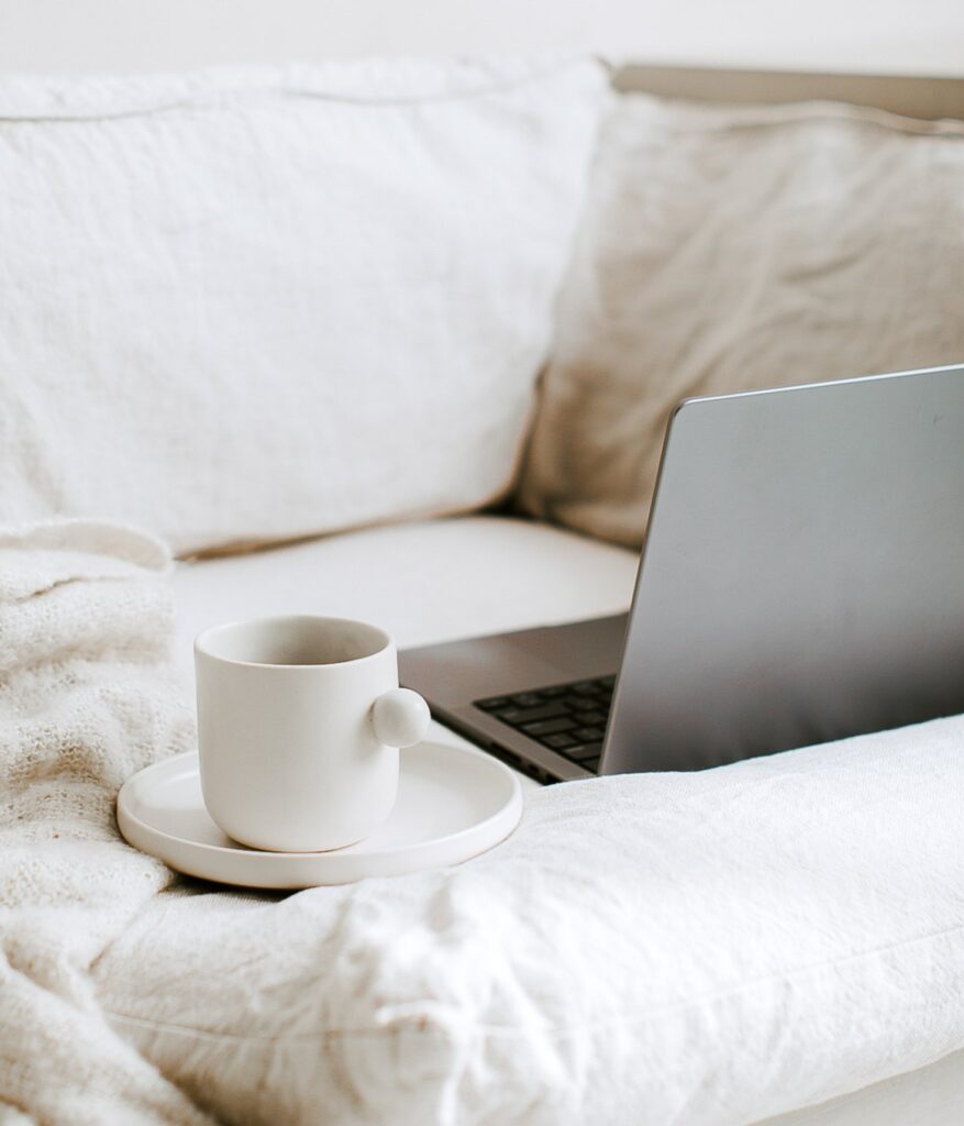 unique looking tea cup on a plate beside a laptop on a couch