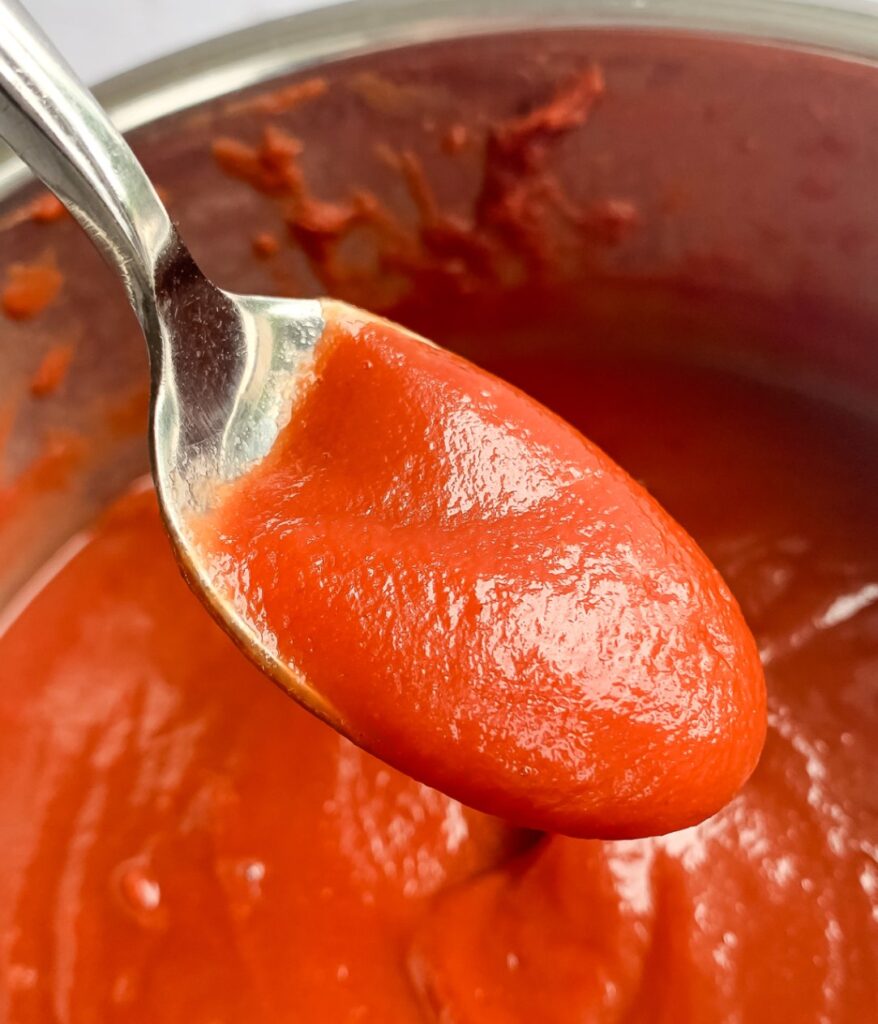 close up of ketchup on spoon coming out of a pot