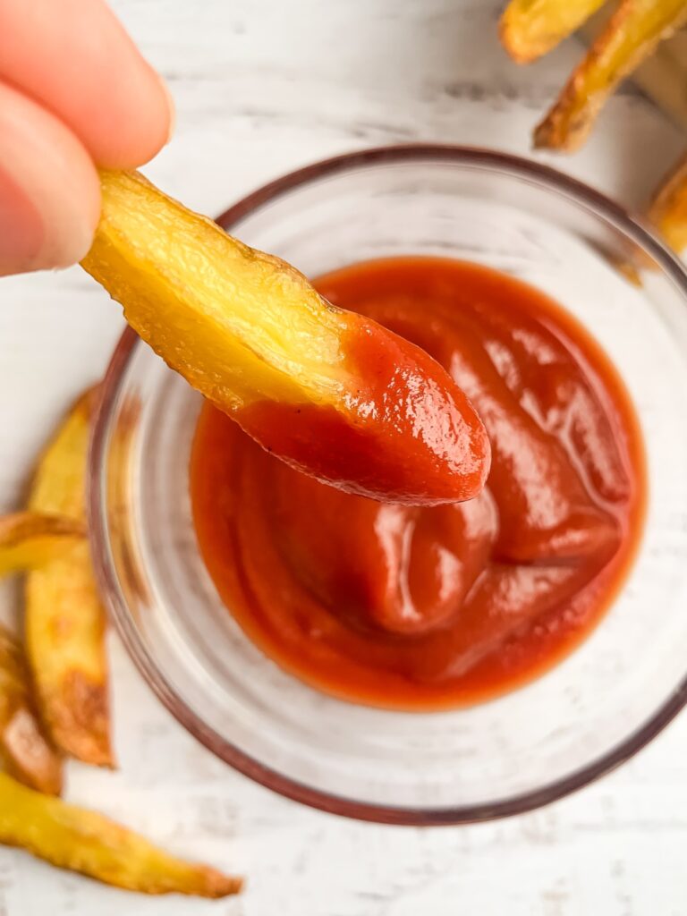 french fry dipped in ketchup in small glass bowl