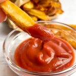 french fry dipped in ketchup in small glass bowl