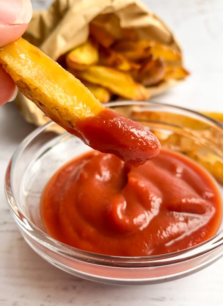 french fry dipped in ketchup in small glass bowl