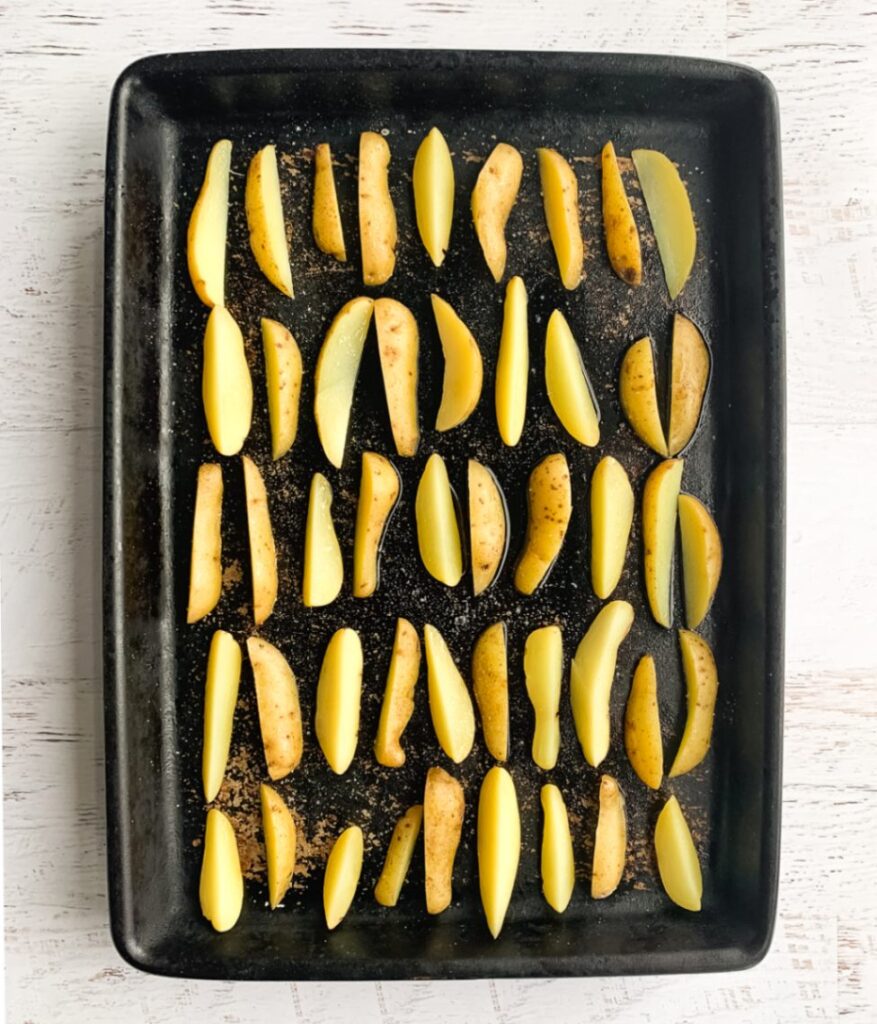 raw potato wedges spaced out evenly on a baking pan