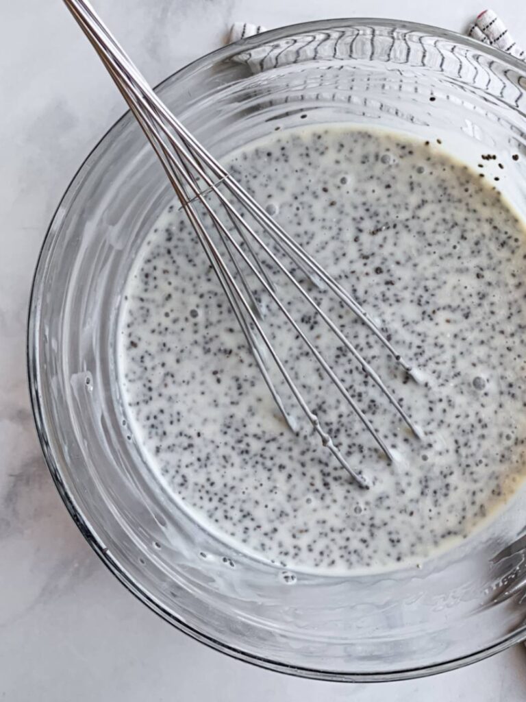 close up of mixing bowl with prepared but unset chia pudding mixture and whisk.