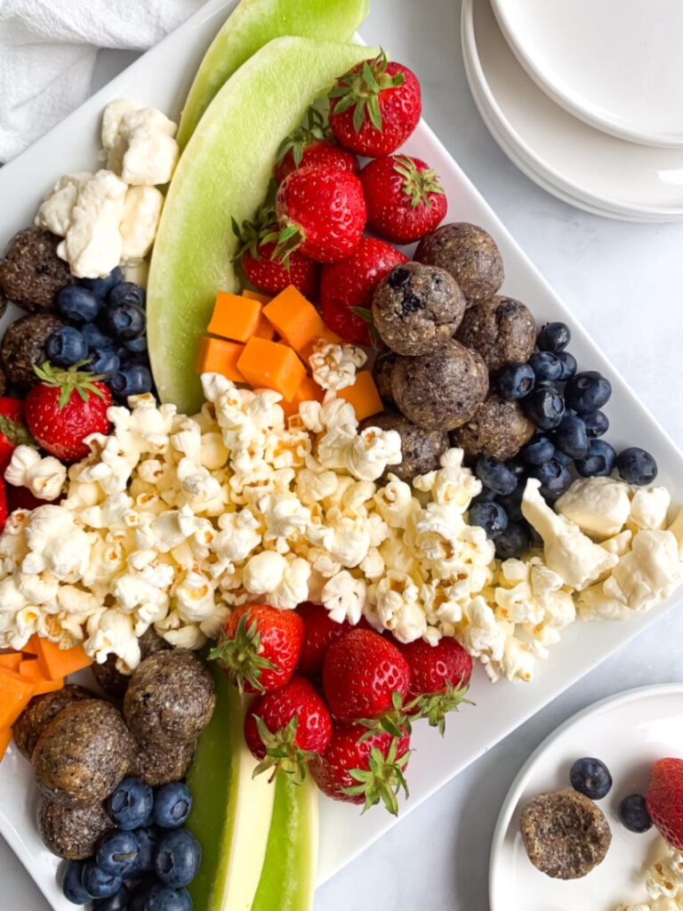 Balanced snack platter with blueberry energy balls, fruit, popcorn and cheese