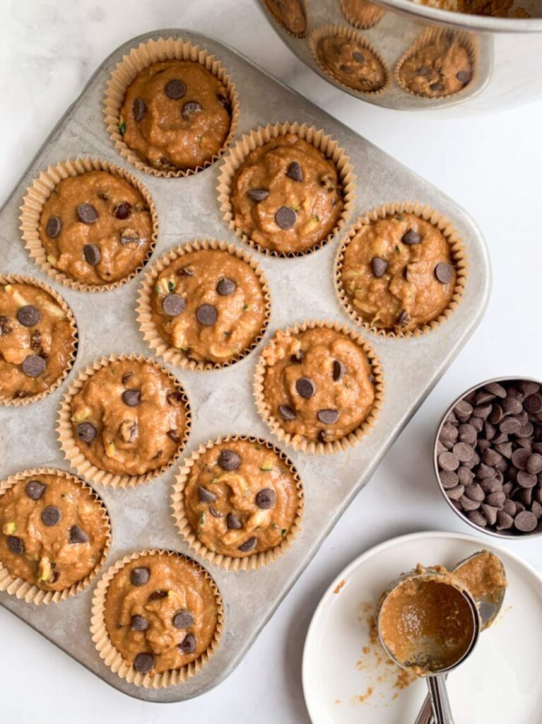 Chocolate chip banana zucchini muffin batter topped with extra chocolate chips and ready for baking.
