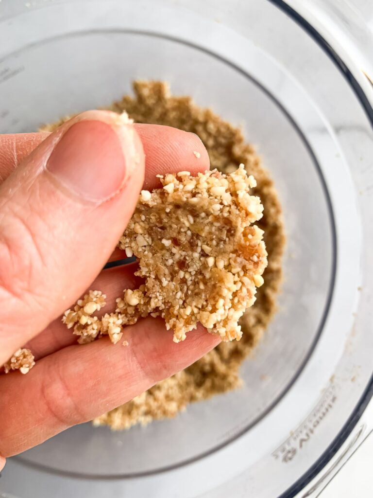 upclose of what the texture of the date and cashew mixture should look like after it's been pressed between fingers before adding lemon zest, vanilla and salt