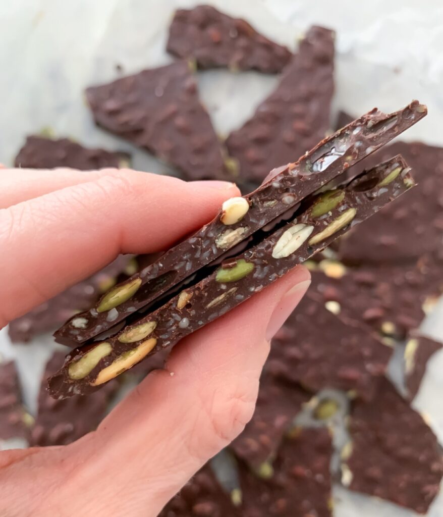 Dark chocolate bark with pumpkin seeds and hemp hearts as a nutrient-dense snack option for kids.