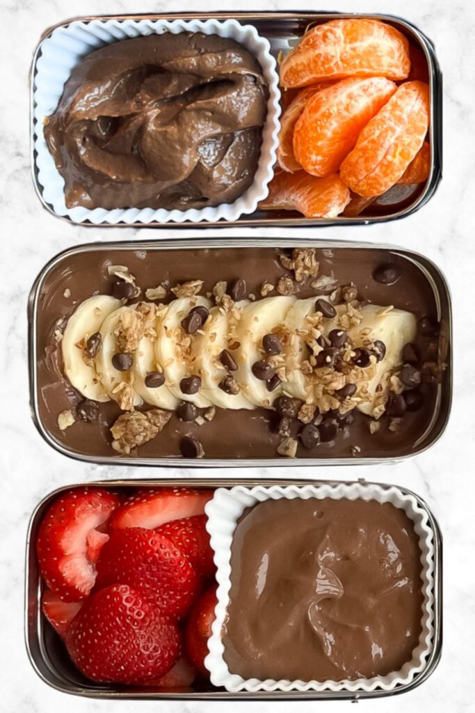 Three chocolate chia pudding snack box ideas served with fruit toppings including strawberries, banana, and mandarin oranges.