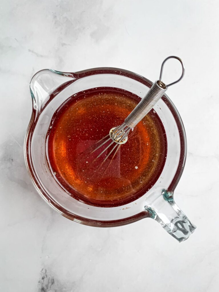 top down of a glass measuring cup with wet ingredients mixed in with a small whisk sticking out the top