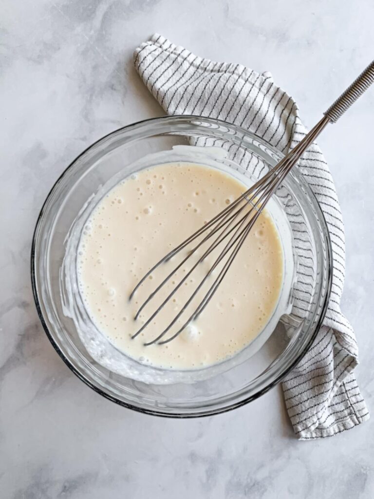 bowl of mixed wet ingredients with a whisk and towel.