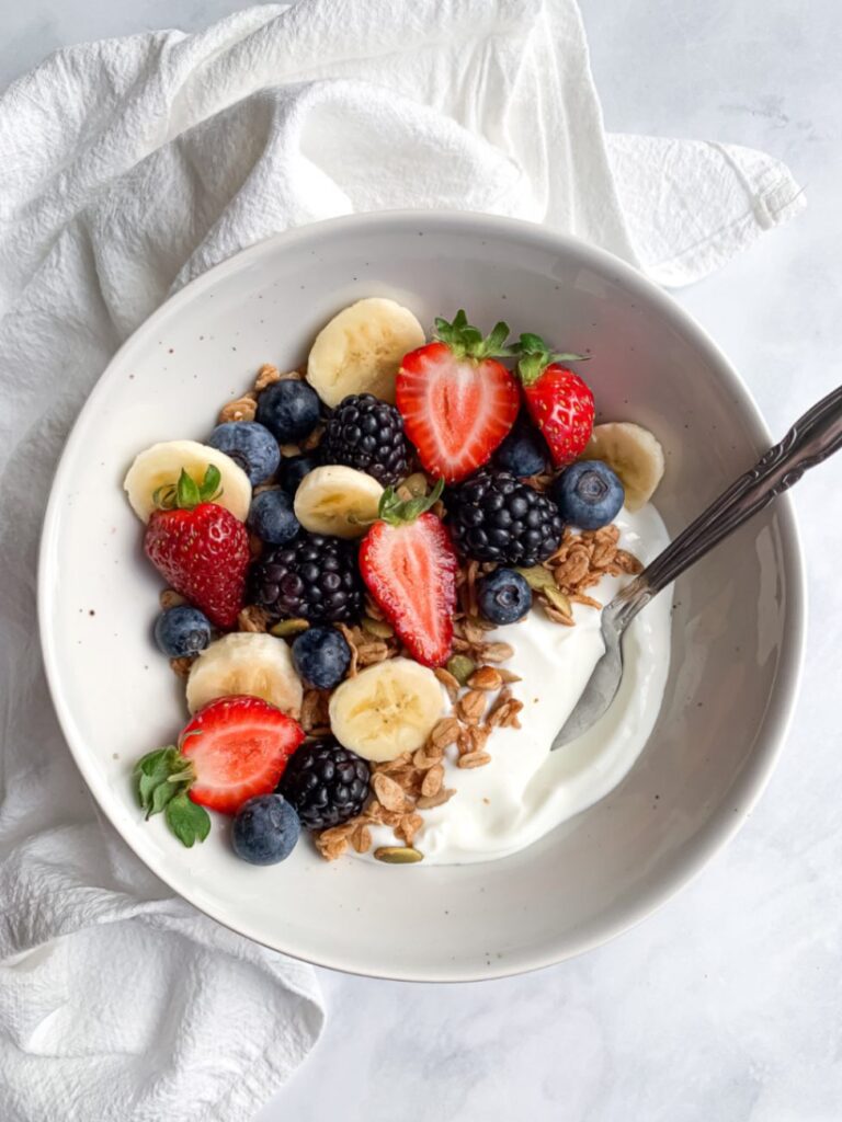 Yogurt topped with berries, banana, and granola as a balanced snack for kids.