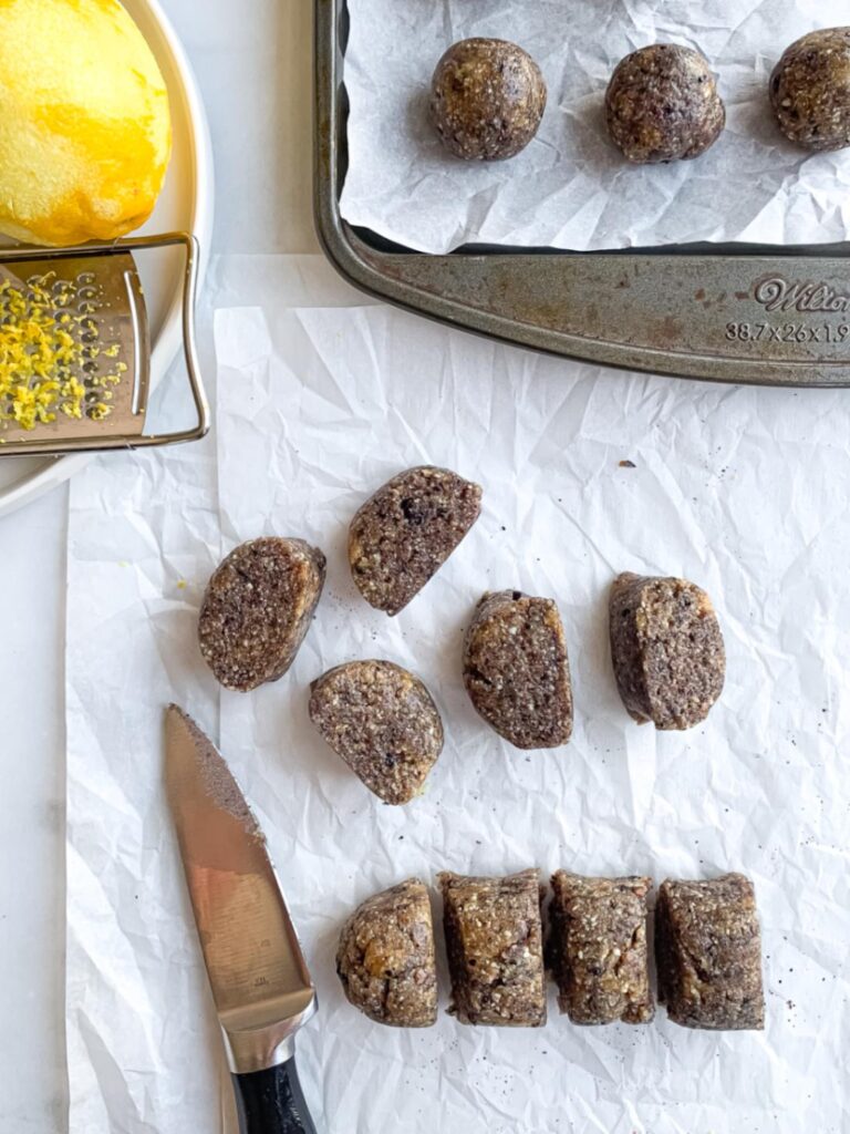 Blueberry energy ball dough rolled into logs and sliced into even portions before rolling