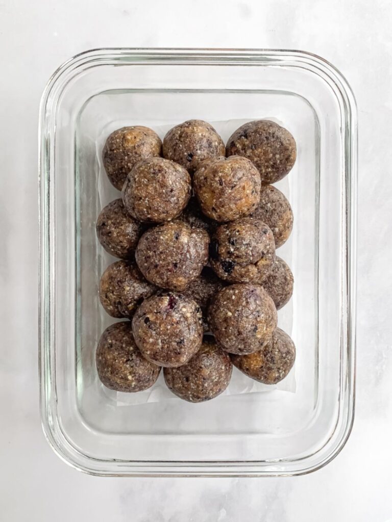 Homemade blueberry energy balls stored in glass and silicone containers for meal prep